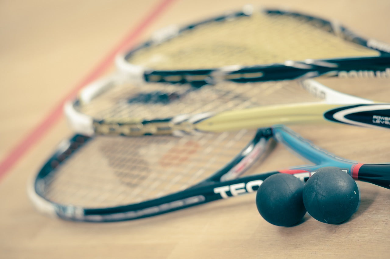 Three squash rackets on the floor of a squash court.